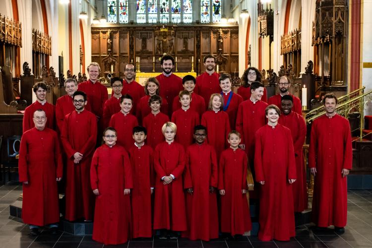 Choir of boys and men in red cassocks standing in Cathedral