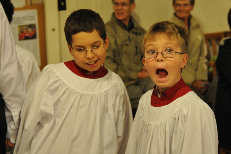 Two young choristers in service cassocks making funny faces