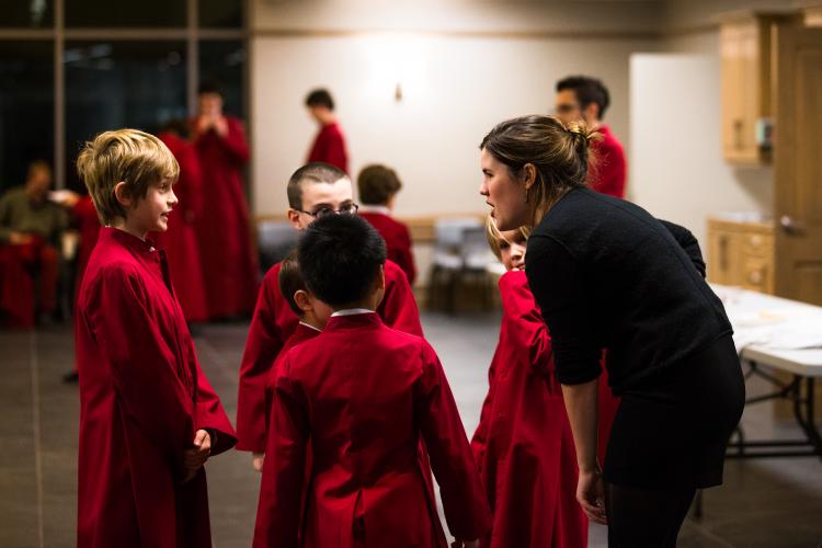 Young choristers in red robes gathered with instructor before performance