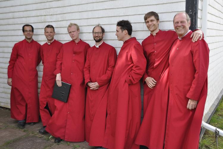 Men of the choir relaxing outside during intermission, wearing red concert robes