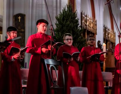 Six boy choristers singing during a performance (2019).