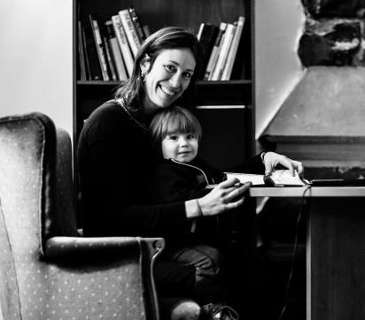 Vanessa Halley in chair with young son and deskwork on her lap